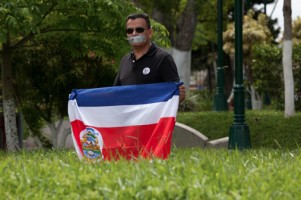 A Tico protests while protected by the flag of Costa Rica
